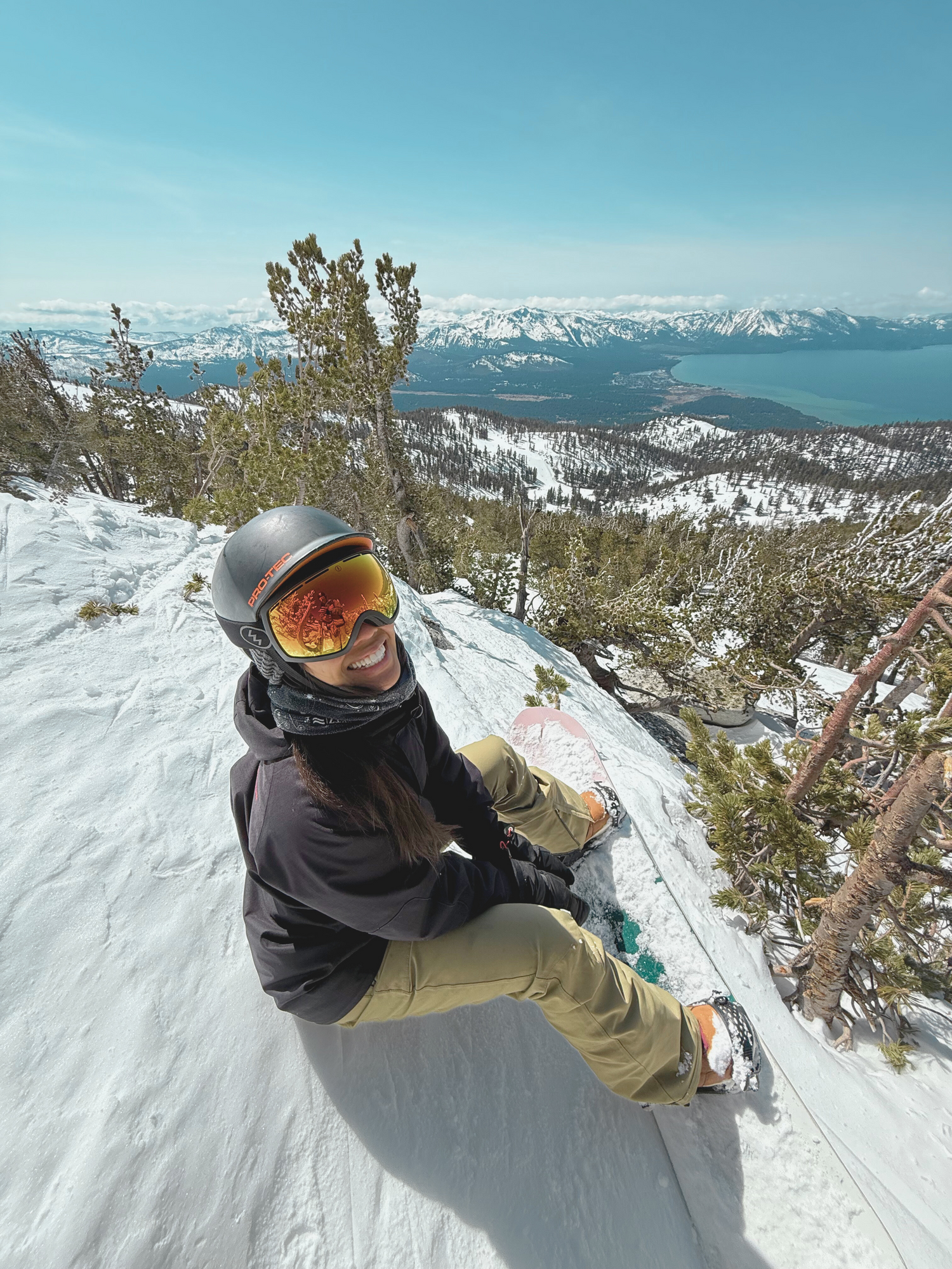 Person on a snowy mountain with snowboard, enjoying the view.